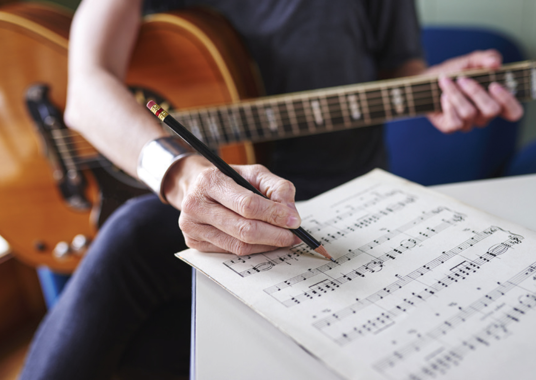 Musician with guitar writing musical notation